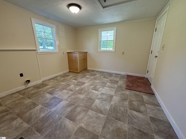 spare room featuring crown molding, baseboards, and stone finish flooring
