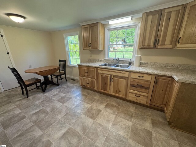 kitchen with a sink, light countertops, stone finish floors, and baseboards