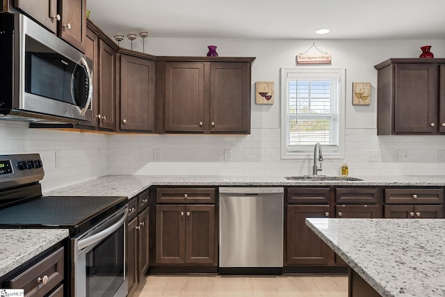 121 Frost Flower Way, Fountain Inn, SC 29644 - kitchen featuring appliances with stainless steel finishes, a sink, dark brown cabinetry, light stone counters, and recessed lighting