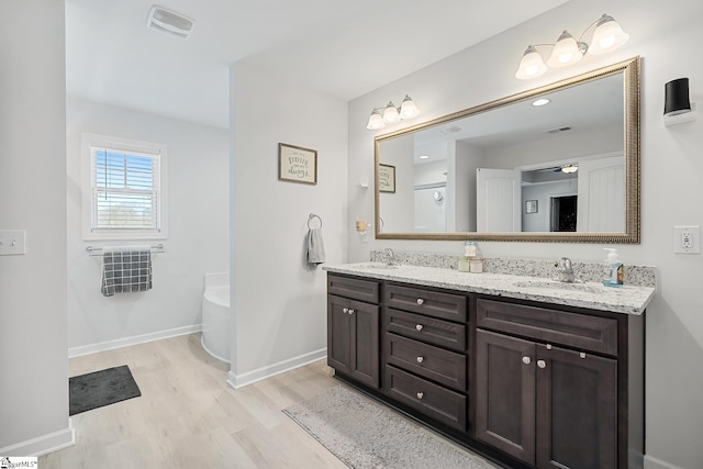 121 Frost Flower Way, Fountain Inn, SC 29644 - bathroom featuring wood finished floors, a tub to relax in, double vanity, and baseboards