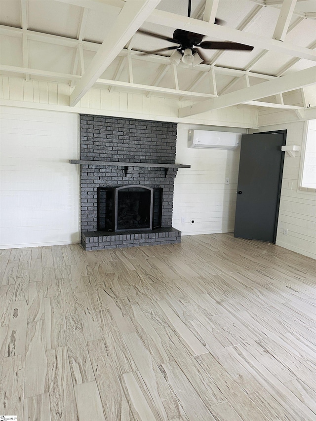 unfurnished living room featuring a wall mounted air conditioner, a brick fireplace, ceiling fan, and wood finished floors
