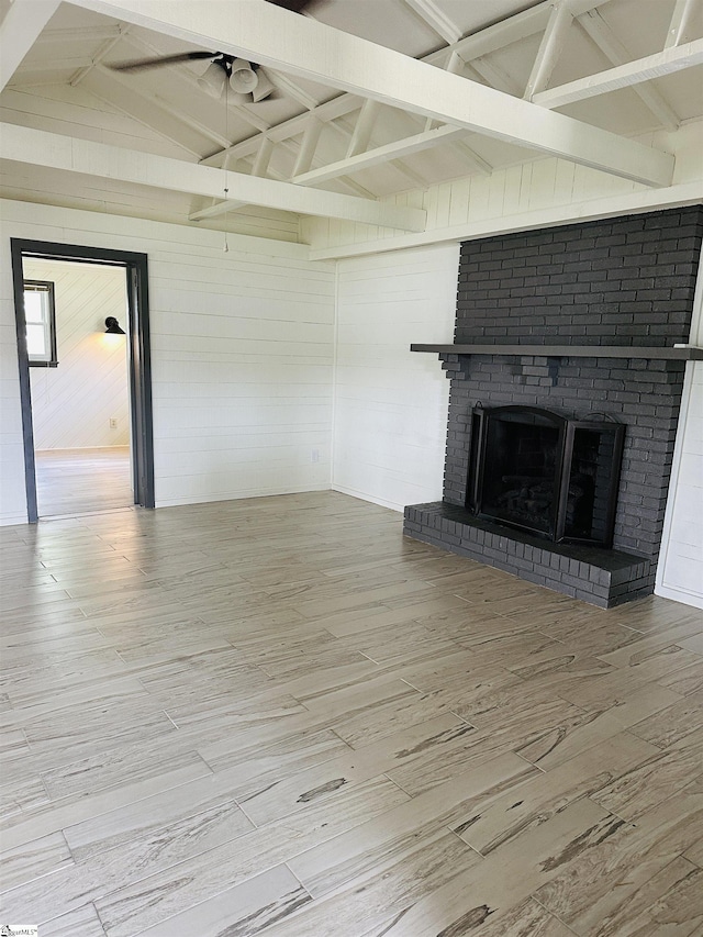 unfurnished living room featuring wood finished floors, a brick fireplace, and wooden walls