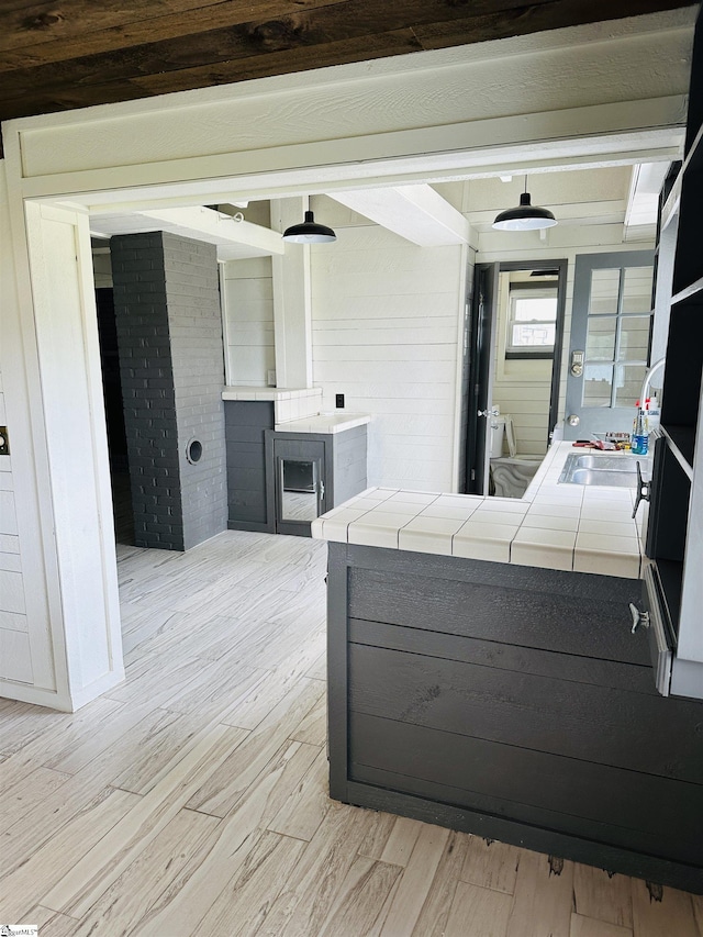 kitchen with tile counters, light wood-style floors, and a fireplace