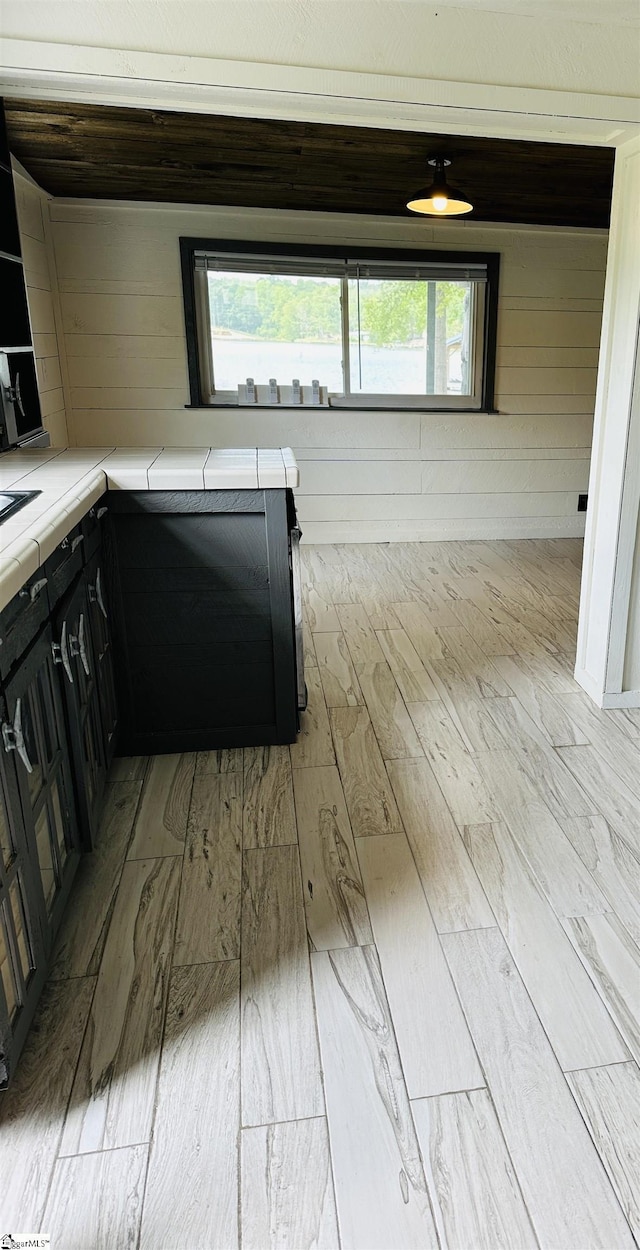 kitchen featuring wood finished floors, tile counters, and dark cabinets