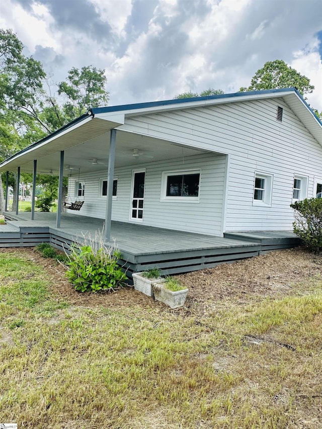 back of property featuring a lawn and a wooden deck