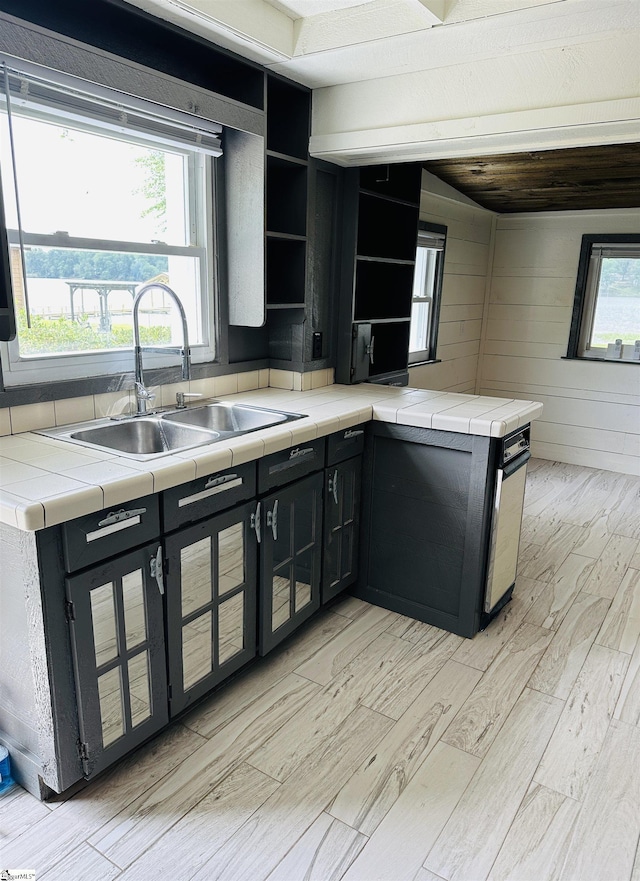 kitchen with light wood-style flooring, open shelves, a sink, and tile countertops