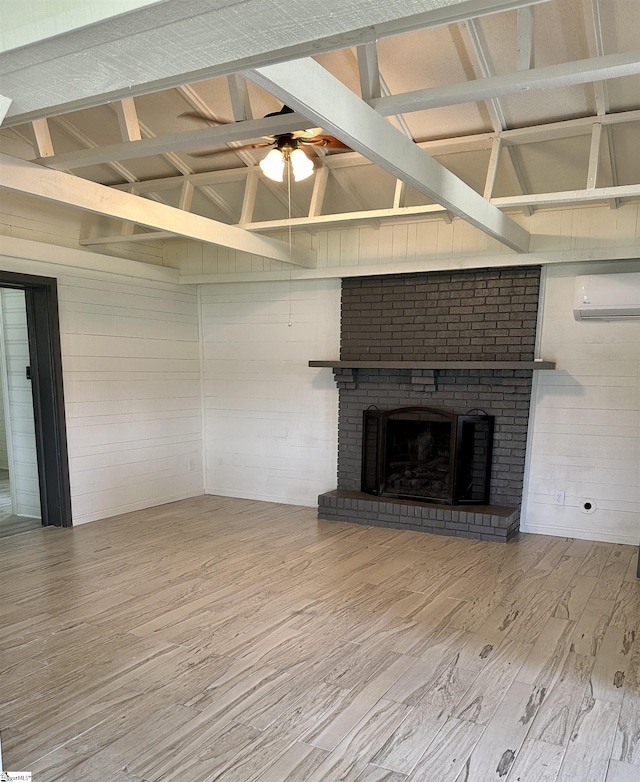 unfurnished living room featuring vaulted ceiling, a wall mounted AC, wood finished floors, a brick fireplace, and wood walls