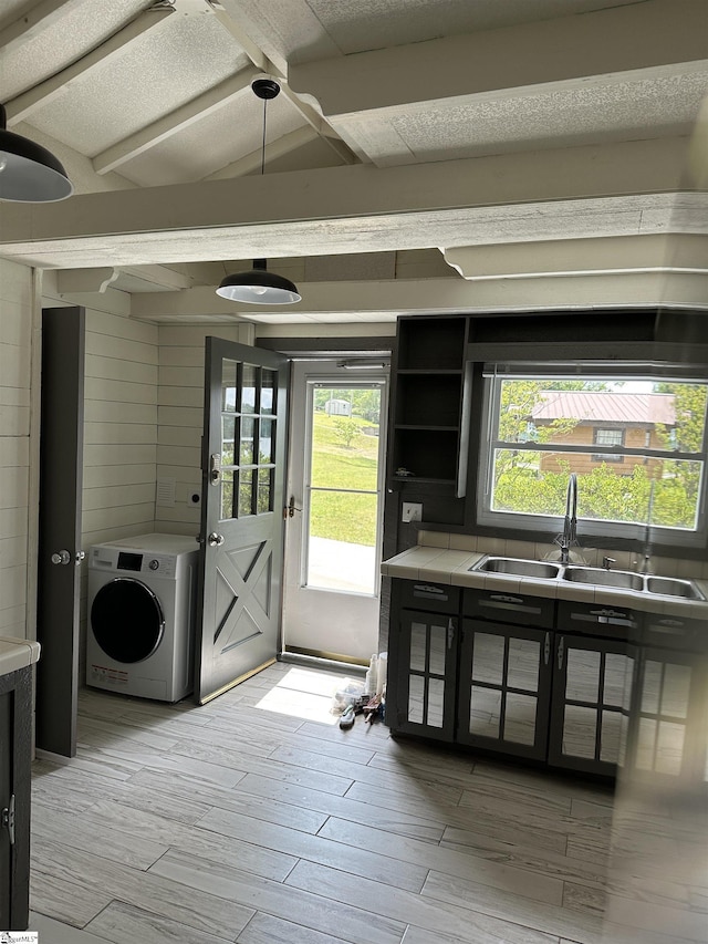 kitchen featuring washer / dryer, a sink, tile countertops, and light wood-style floors