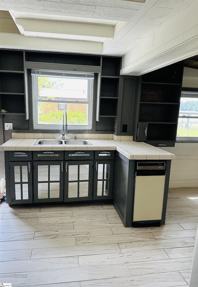 kitchen featuring open shelves, a sink, tile countertops, and light wood-type flooring