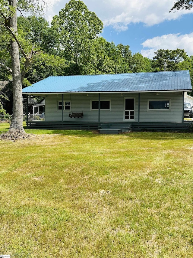 back of house featuring metal roof and a yard