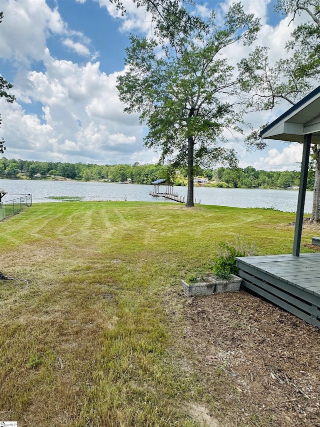 view of grassy yard featuring a deck with water view