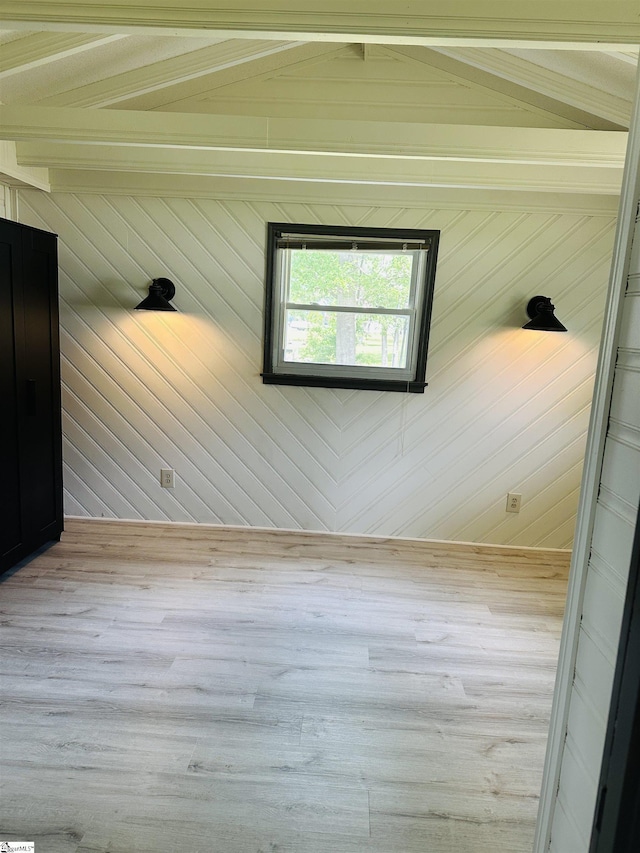spare room featuring beamed ceiling, wood finished floors, and wooden walls