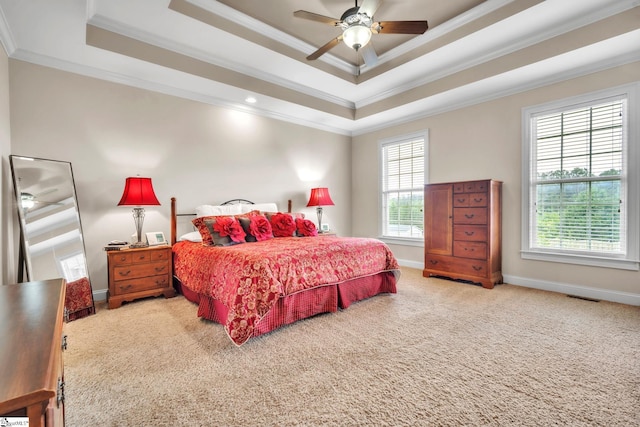 carpeted bedroom featuring crown molding, a tray ceiling, baseboards, and a ceiling fan