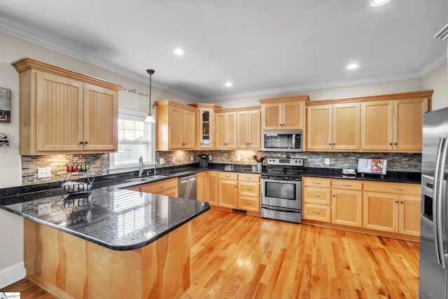 kitchen featuring stainless steel appliances, a sink, light brown cabinets, a peninsula, and ornamental molding