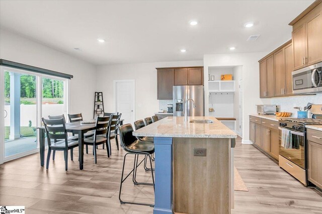 204 Hazelcroft Dr, Fountain Inn, SC 29644 - kitchen featuring stainless steel appliances, light wood-type flooring, light stone counters, a sink, and an island with sink