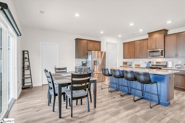 204 Hazelcroft Dr, Fountain Inn, SC 29644 - kitchen with appliances with stainless steel finishes, light wood-style flooring, tasteful backsplash, a kitchen island with sink, and recessed lighting