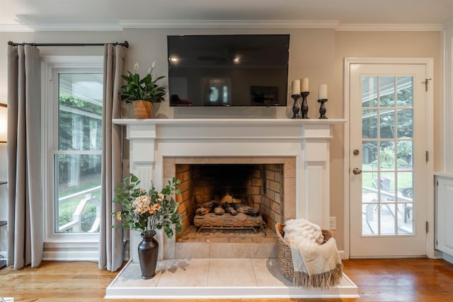 detailed view of a tiled fireplace, ornamental molding, and wood finished floors
