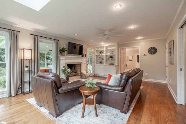 living area featuring ornamental molding, plenty of natural light, wood finished floors, a fireplace with raised hearth, and recessed lighting