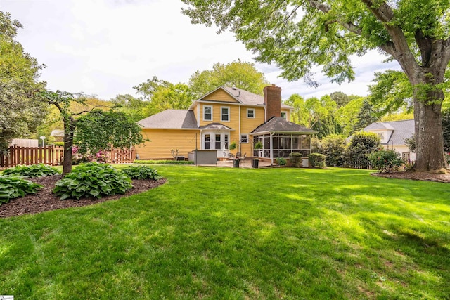 rear view of property with a sunroom, a chimney, and a patio