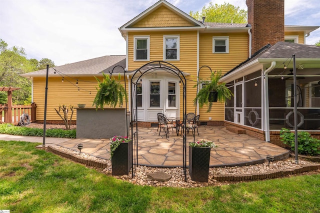 back of property with a patio, a sunroom, and roof with shingles