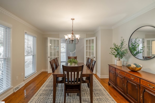 dining space featuring wood finished floors, a chandelier, ornamental molding, and baseboards