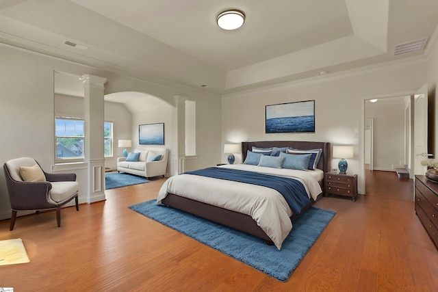 9 Sheldrake Pl, Simpsonville, SC 29681 - bedroom featuring decorative columns, wood finished floors, arched walkways, a raised ceiling, and crown molding