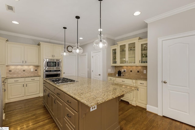 kitchen featuring appliances with stainless steel finishes, backsplash, a kitchen island, glass insert cabinets, and light stone countertops