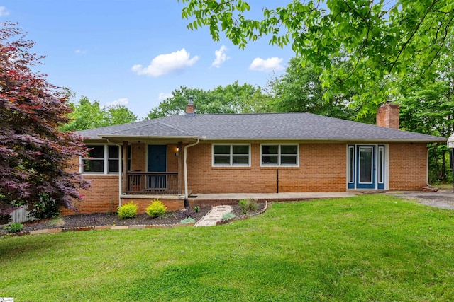 ranch-style home featuring a chimney, a front lawn, brick siding, and a shingled roof