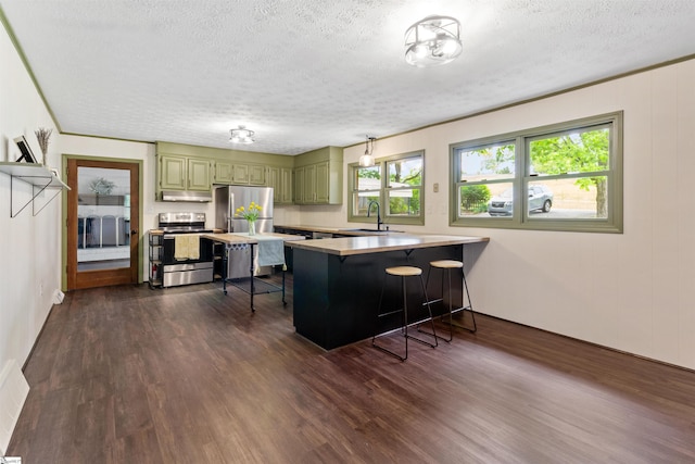 kitchen with stainless steel appliances, a peninsula, a sink, a textured ceiling, and a breakfast bar area
