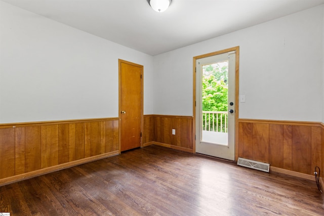 empty room with wood finished floors, a wainscoted wall, and wooden walls