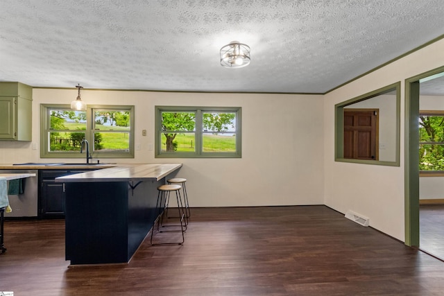 kitchen featuring dishwasher, a kitchen breakfast bar, a peninsula, a textured ceiling, and dark wood finished floors