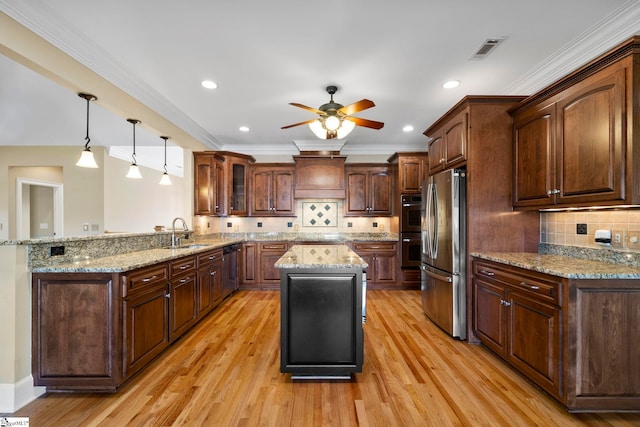 kitchen featuring appliances with stainless steel finishes, a sink, a peninsula, ceiling fan, and light wood finished floors