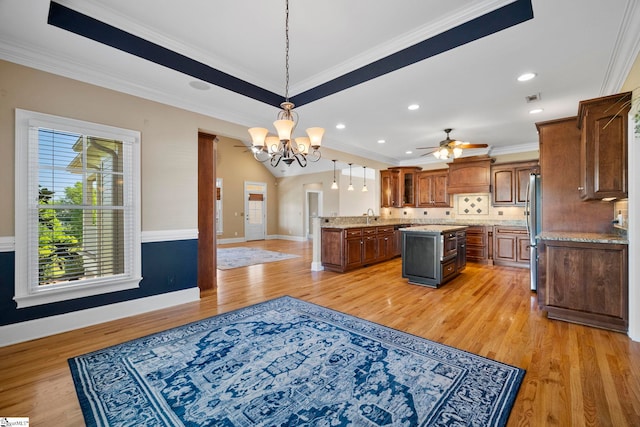 kitchen featuring freestanding refrigerator, a kitchen island, a chandelier, light wood-style flooring, and ornamental molding