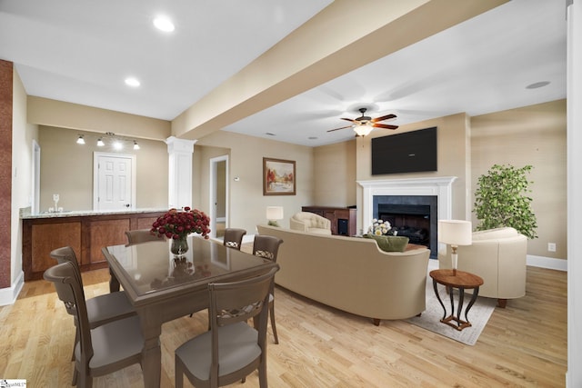 dining space featuring light wood-style floors, baseboards, a fireplace, ceiling fan, and recessed lighting