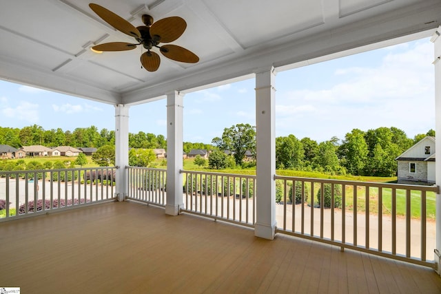 wooden terrace featuring a ceiling fan and view of wooded area