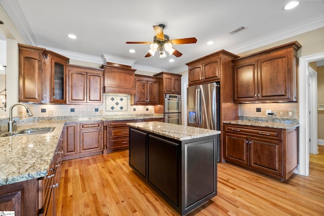 kitchen with a sink, appliances with stainless steel finishes, a ceiling fan, light wood-style floors, and tasteful backsplash