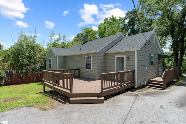 back of house with a wooden deck, a shingled roof, and a chimney