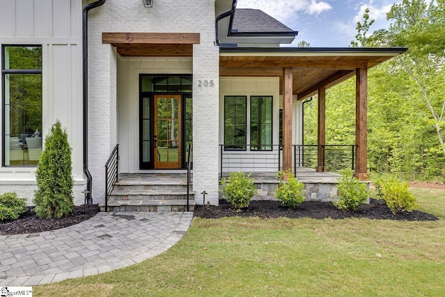 205 Fairview Dr, Greenville, SC 29609 - view of exterior entry with covered porch, a lawn, and board and batten siding