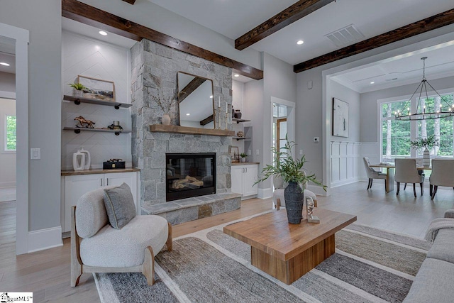 205 Fairview Dr, Greenville, SC 29609 - living room featuring beam ceiling, light wood-style flooring, healthy amount of natural light, a chandelier, and a stone fireplace