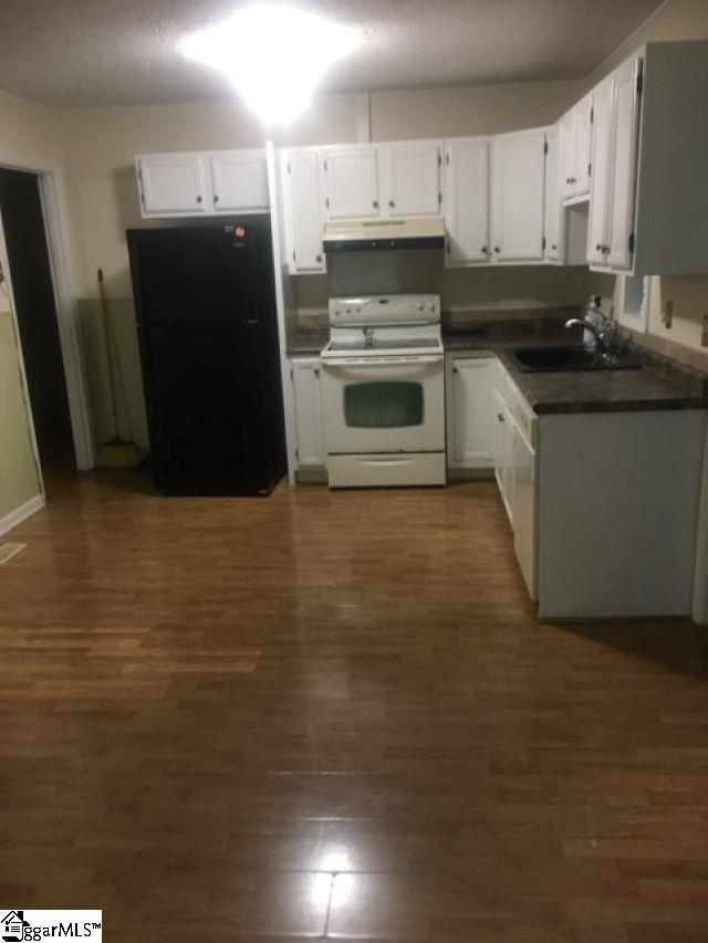 413 S Florida Ave, Greenville, SC 29611 - kitchen with white appliances, under cabinet range hood, a sink, dark countertops, and white cabinetry