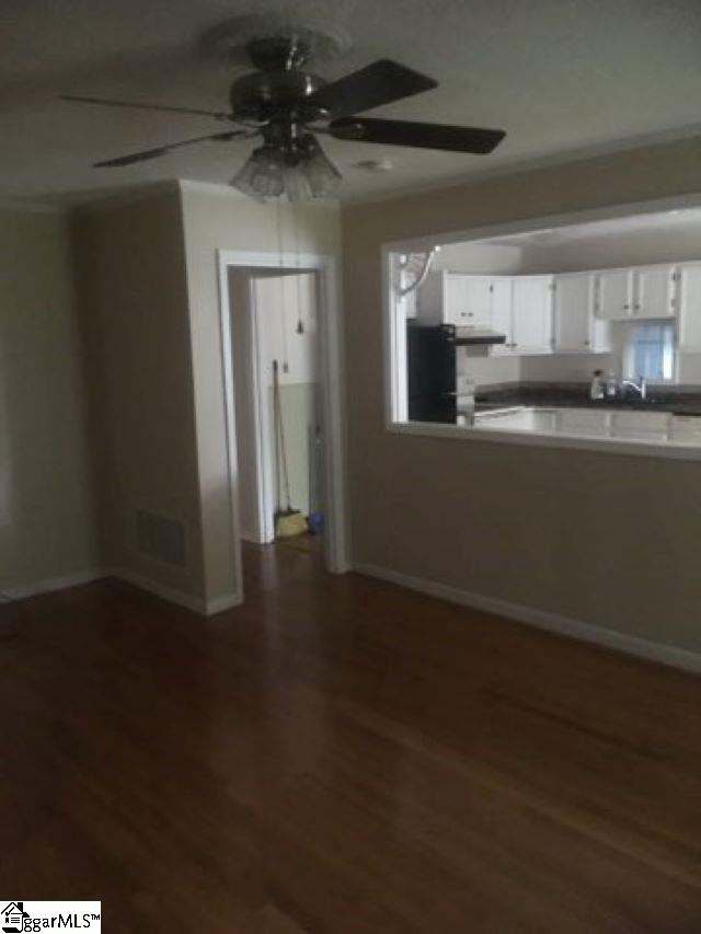 413 S Florida Ave, Greenville, SC 29611 - unfurnished living room featuring a ceiling fan, wood finished floors, and baseboards