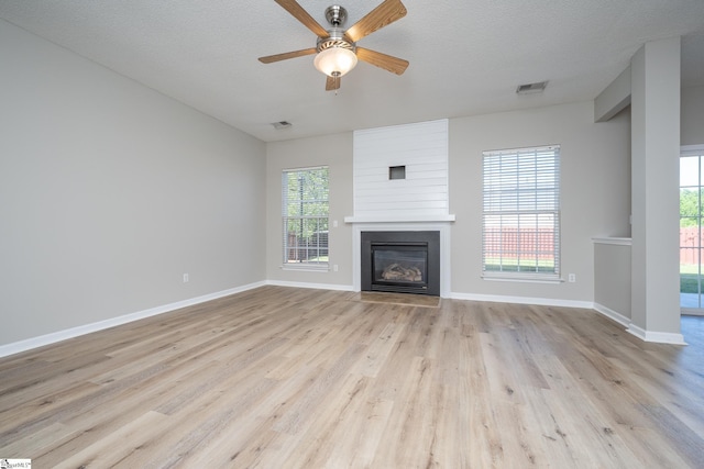 300 Stillwater Ct, Simpsonville, SC 29681 - unfurnished living room featuring a large fireplace, light wood-style floors, ceiling fan, and plenty of natural light