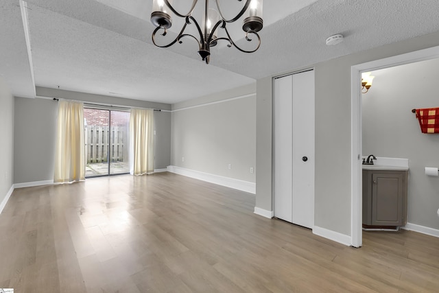 2530 E N St Unit 13K, Greenville, SC 29615 - unfurnished living room with a chandelier, a textured ceiling, light wood finished floors, and baseboards