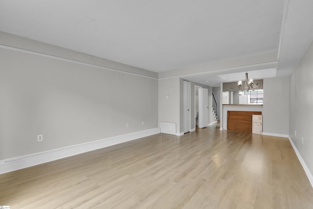 2530 E N St Unit 13K, Greenville, SC 29615 - unfurnished living room with a chandelier, light wood-style floors, baseboards, and stairway