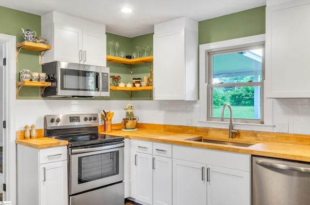 101 Kenilworth Ct, Greenville, SC 29615 - kitchen with appliances with stainless steel finishes, open shelves, wooden counters, a sink, and decorative backsplash