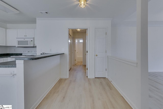 kitchen featuring white appliances, dark countertops, white cabinetry, light wood-style flooring, and baseboards