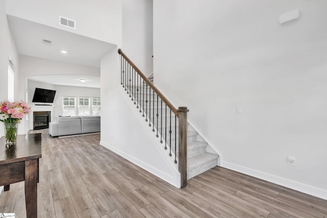 153 Coppermine Dr, Easley, SC 29642 - stairs featuring wood finished floors, baseboards, a glass covered fireplace, arched walkways, and recessed lighting