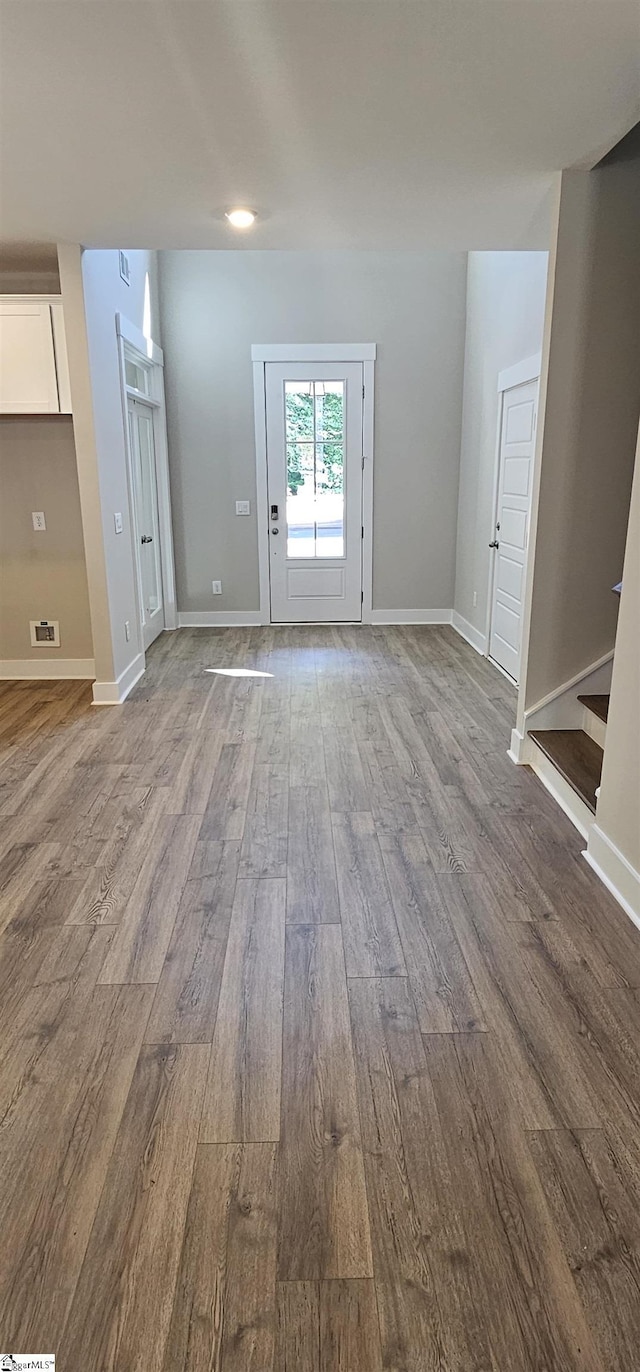 unfurnished living room with wood finished floors, stairs, and baseboards