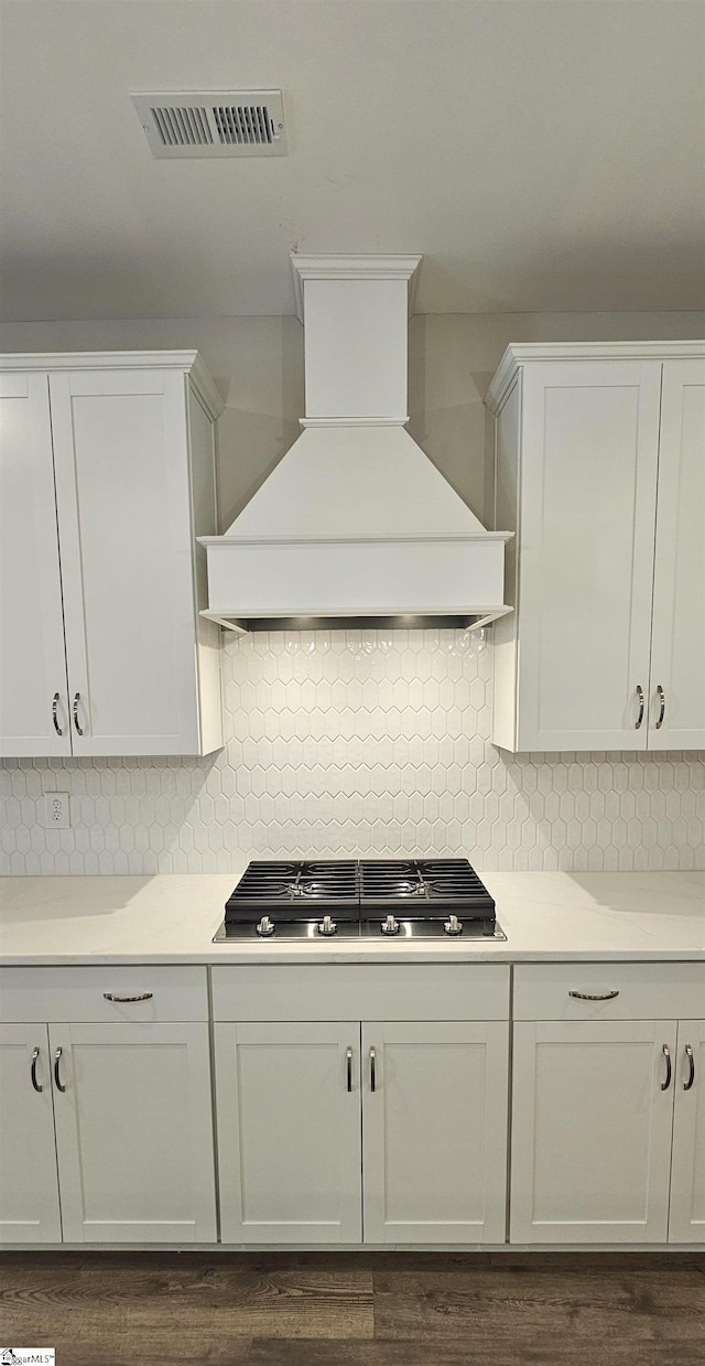 kitchen featuring custom exhaust hood, stainless steel gas cooktop, light countertops, and backsplash