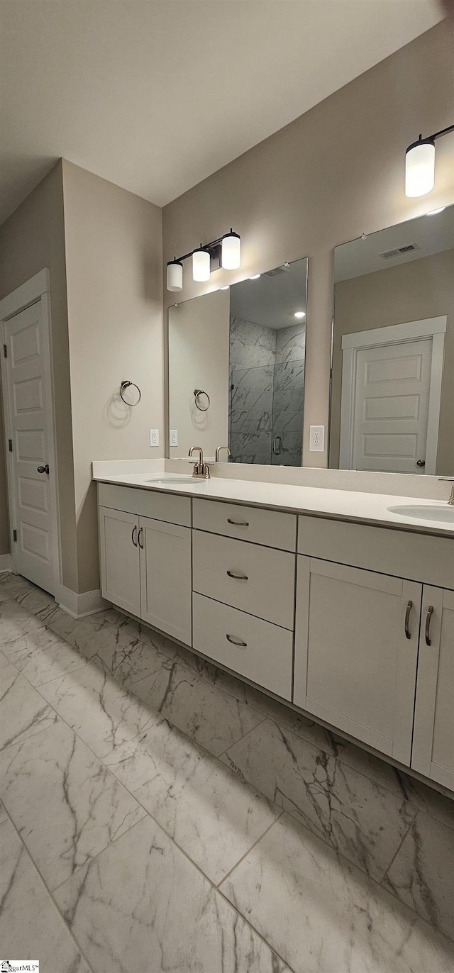 bathroom with marble look tiles, a marble finish shower, double vanity, and baseboards